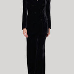 A model wearing a black velvet double-breasted blazer and matching wide-leg trousers from Parosh against a solid light gray background.