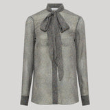 A gray and black herringbone patterned long-sleeve blouse with a large bow tie at the collar, from Gabriela Hearst, shown on a neutral light gray background.