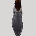 A top-down view of a black leather pointed-toe western boot with decorative stitching and a pull tab, shown on a light gray background.