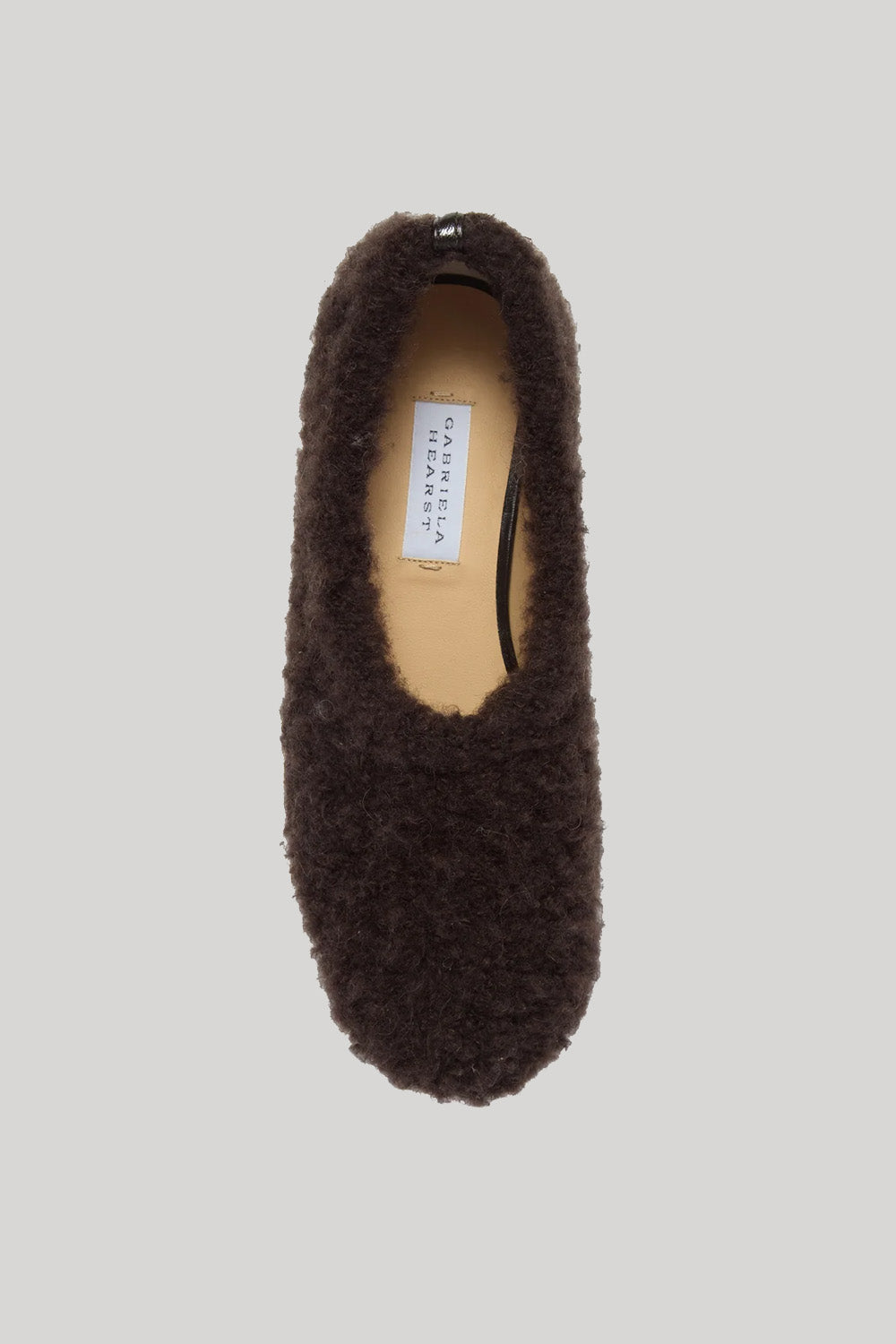 A top view of a fuzzy brown cashmere slipper shown on a plain grey background