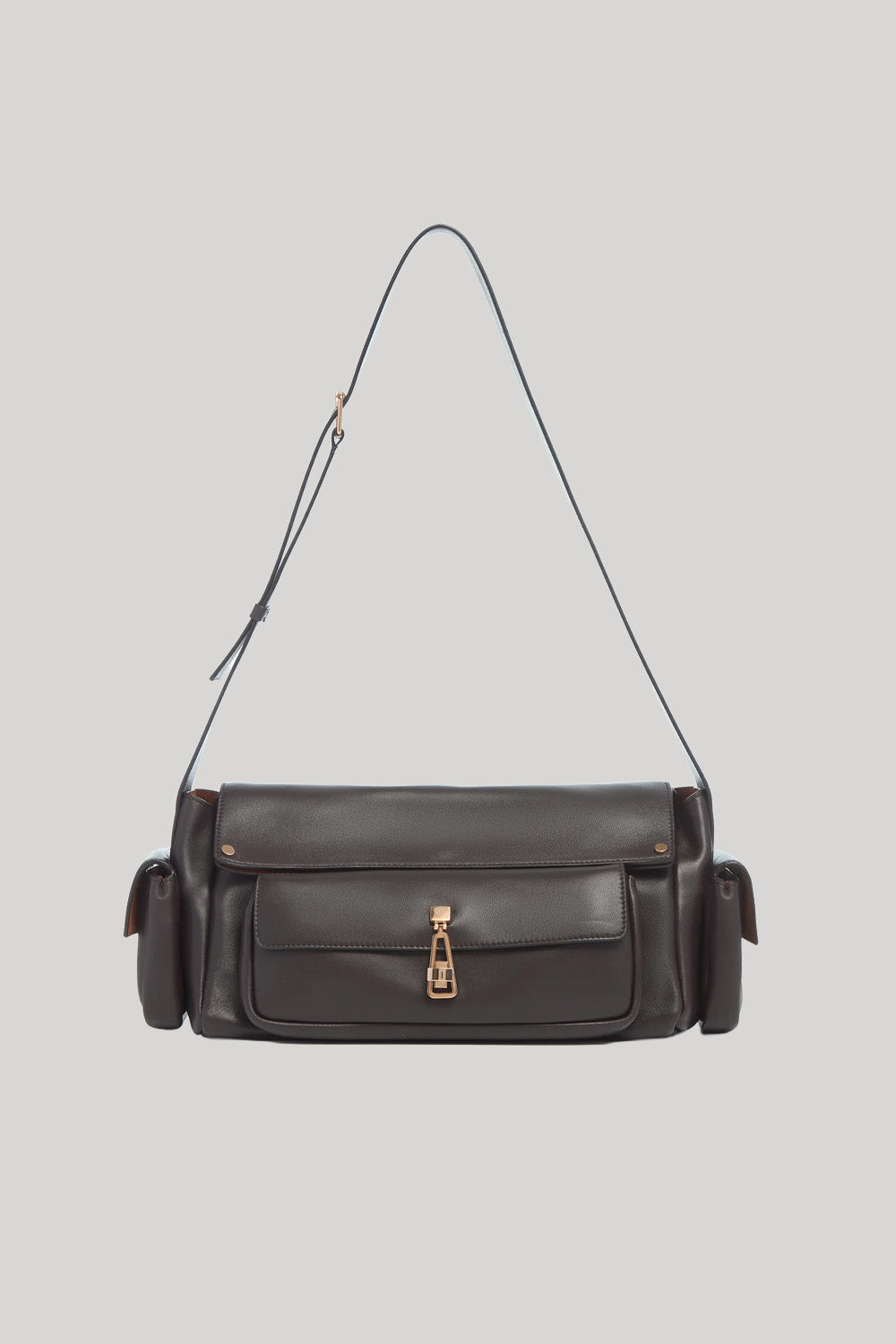A dark brown leather shoulder bag from Gabriela Hearst with a front flap pocket, gold-tone hardware, and a thin matching leather strap, shown against a solid light gray background.