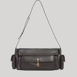 A dark brown leather shoulder bag from Gabriela Hearst with a front flap pocket, gold-tone hardware, and a thin matching leather strap, shown against a solid light gray background.