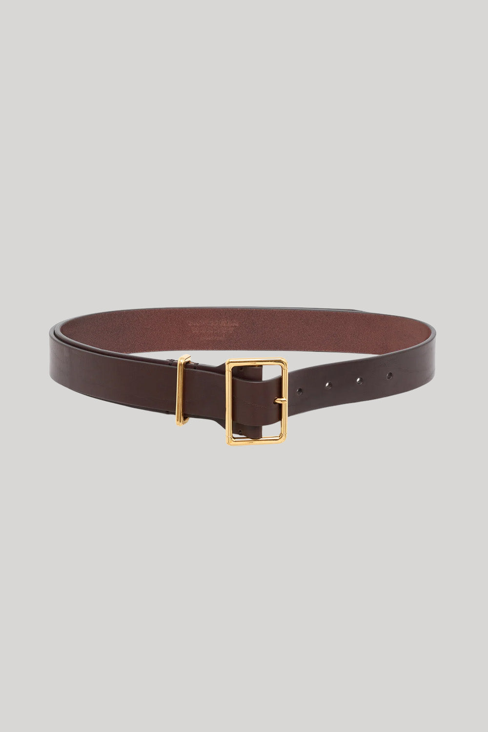 A dark brown leather belt with a gold-tone buckle, from Gabriela Hearst, displayed on a neutral light gray background.