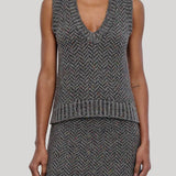 A model wearing a sleeveless knit vest and matching skirt in a gray and black herringbone pattern, from Gabriela Hearst shown from the neck down against a solid light gray background.