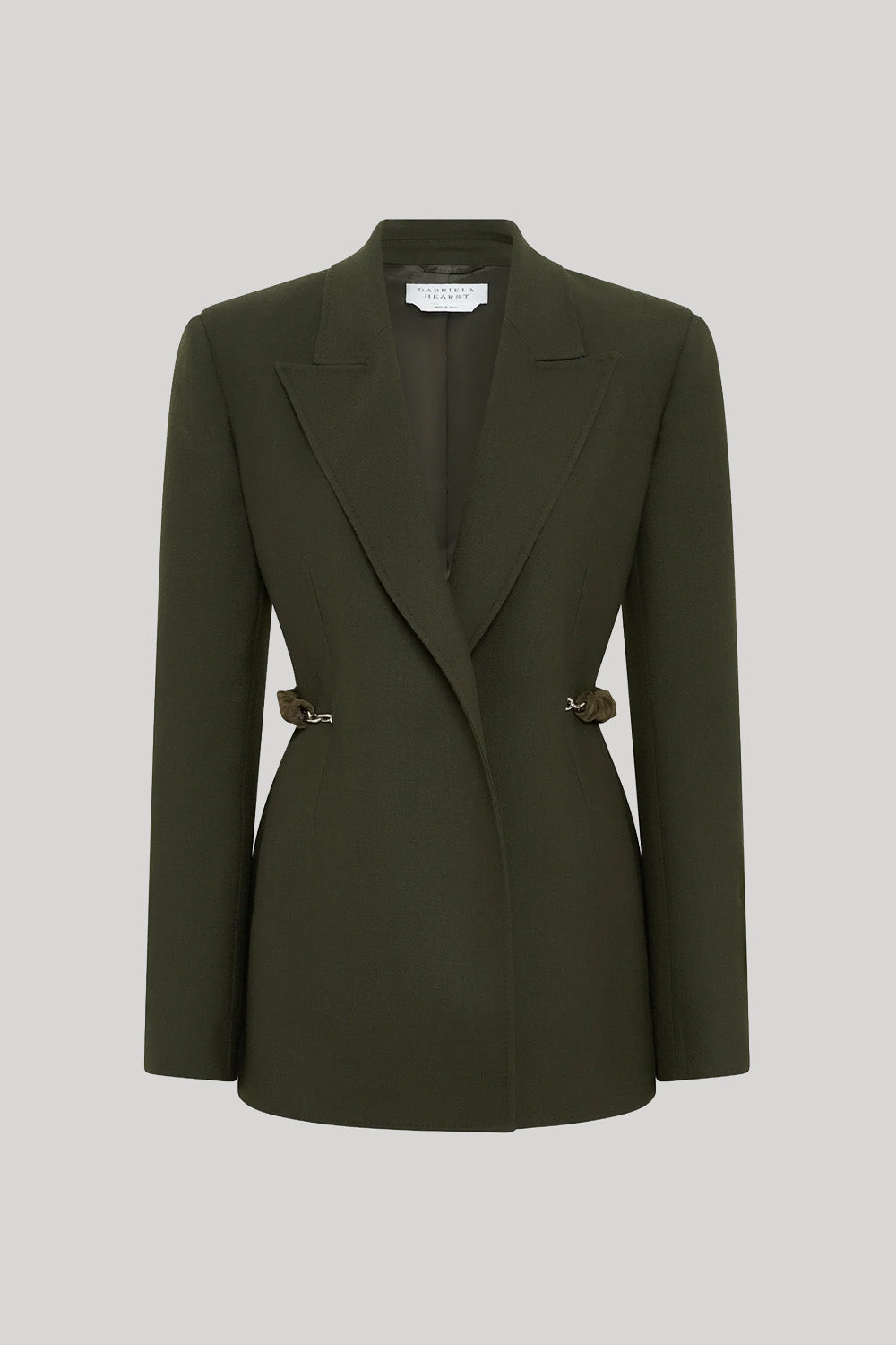 An olive green single-breasted blazer with structured shoulders and decorative gold-tone chains on the waist, from Gabriela Hearst, displayed on a neutral light gray background.