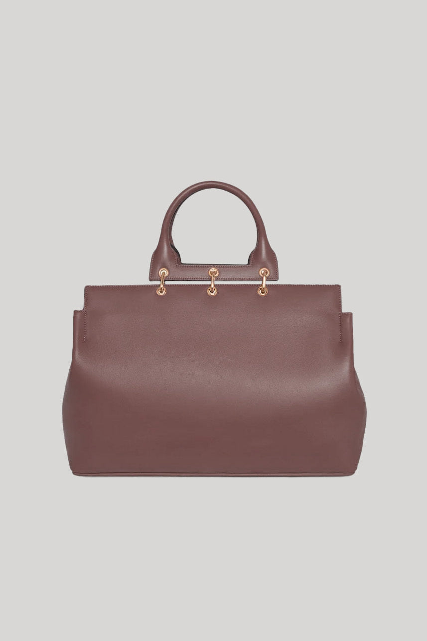 Brown leather handbag with gold hardware on a light gray background