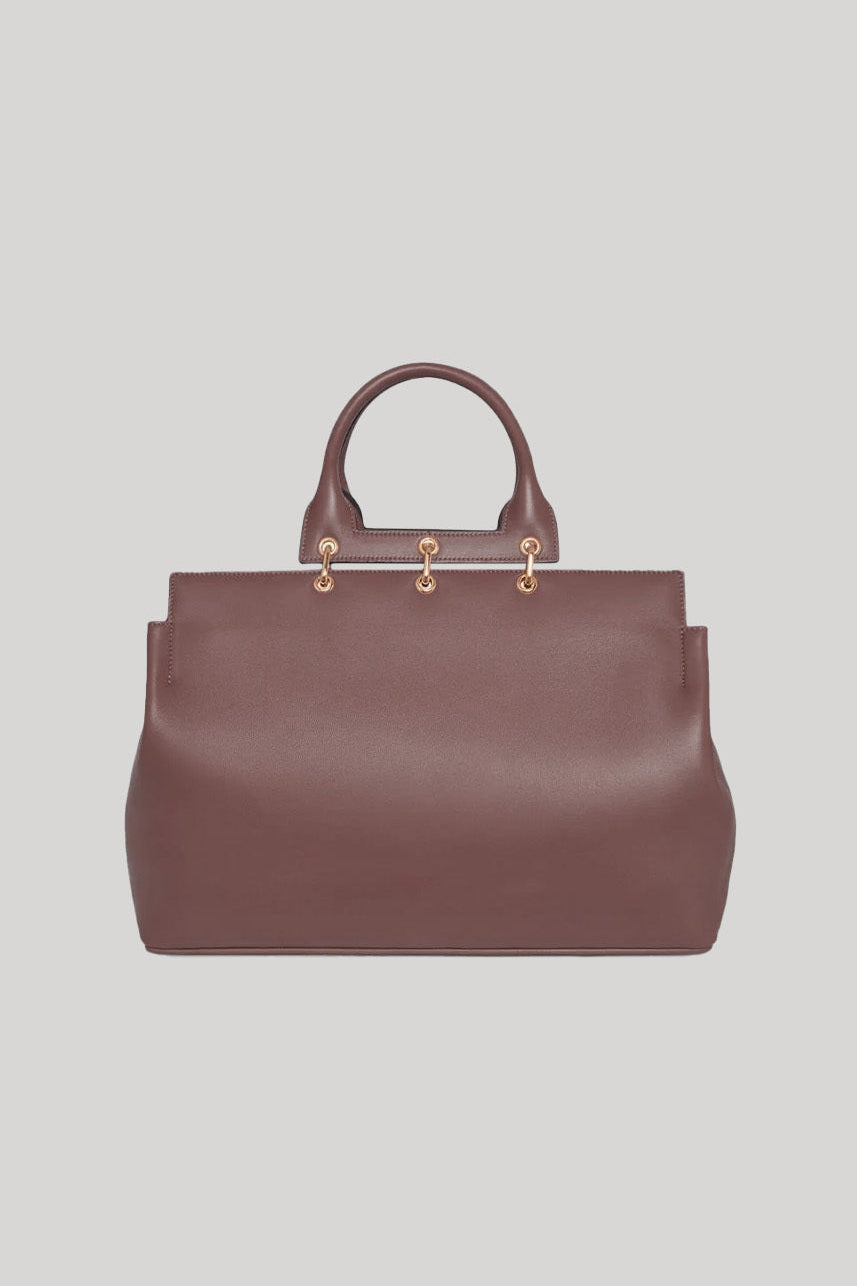 Brown leather handbag with gold hardware on a light gray background