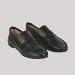A pair of black leather penny loafers with a smooth finish, displayed on a solid light gray background.