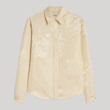A light beige long-sleeve button-up shirt with a subtle tonal floral jacquard pattern from Jil Sander. Displayed flat against a neutral gray background.