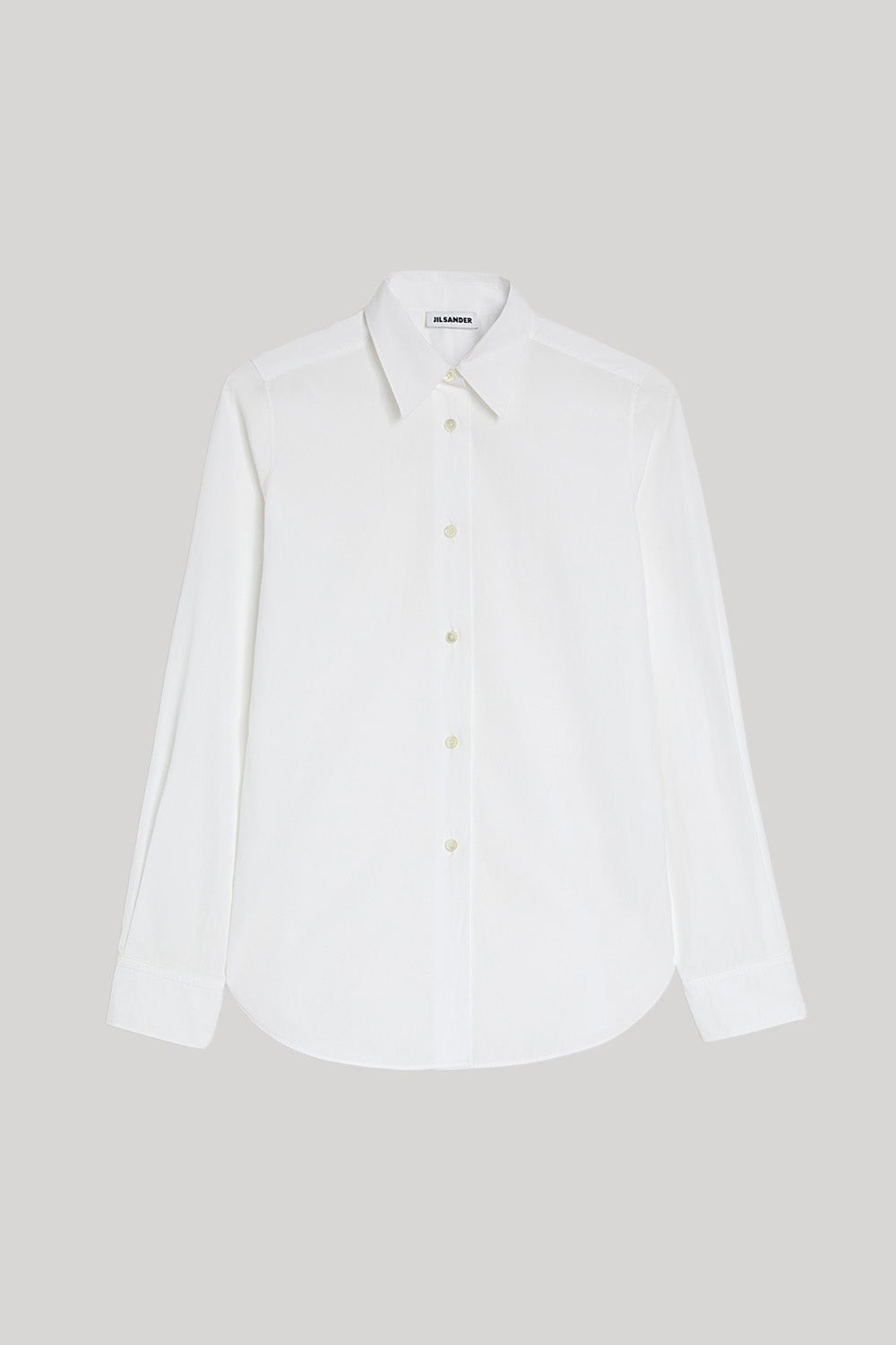 A white long-sleeve Jil Sander button-up shirt with a pointed collar and matching buttons, displayed flat against a solid light gray background.