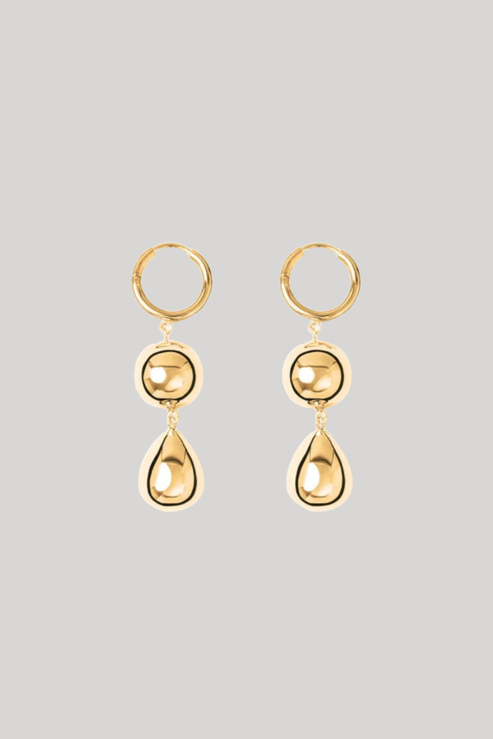 A pair of gold drop hoop earrings with a circular bead and teardrop pendant, shown against a solid light gray background.