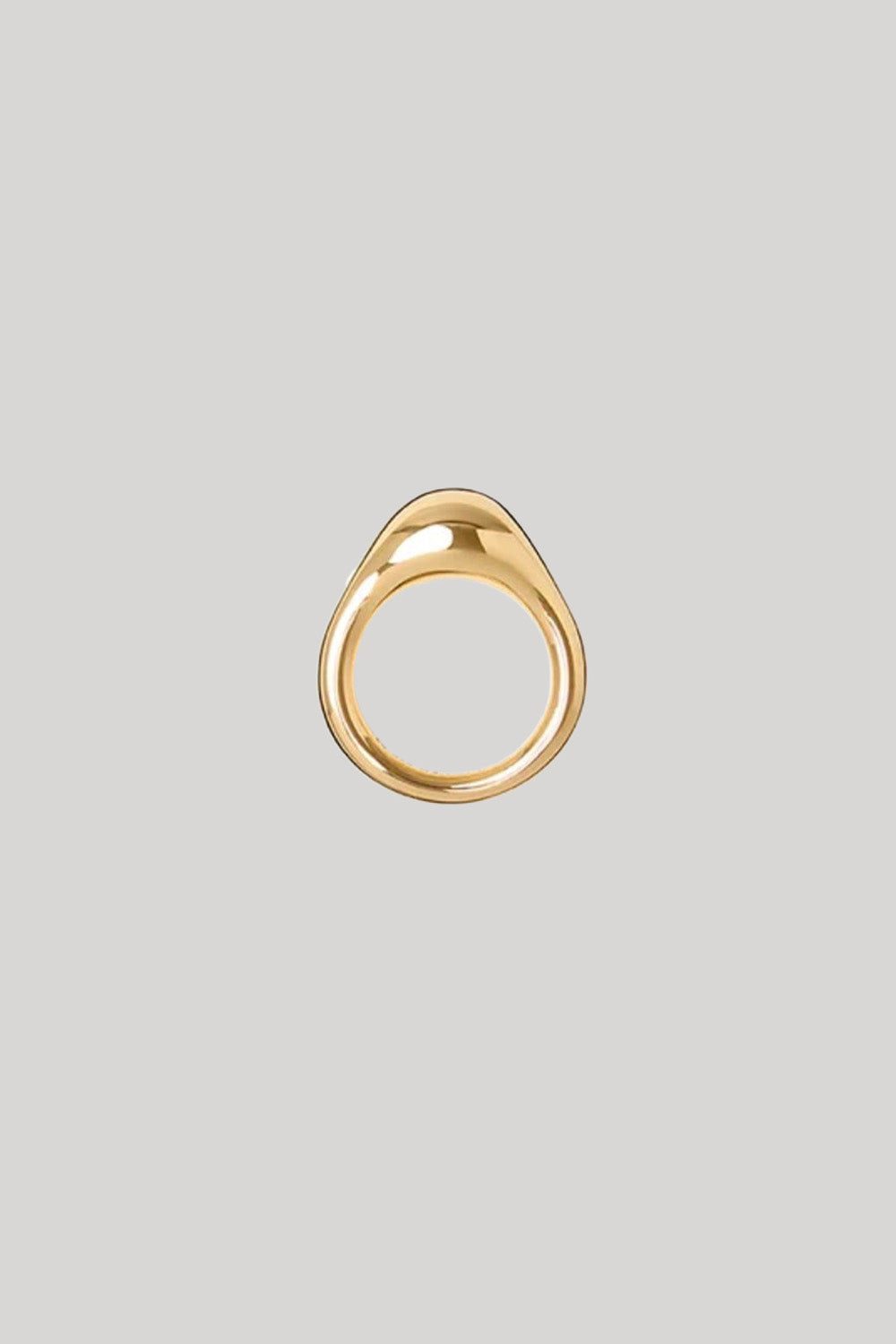 A gold teardrop-shaped ring with a smooth, polished finish, centered on a solid light gray background.