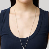A silver teardrop pendant necklace worn by a model in a navy blue tank top against a light gray background.