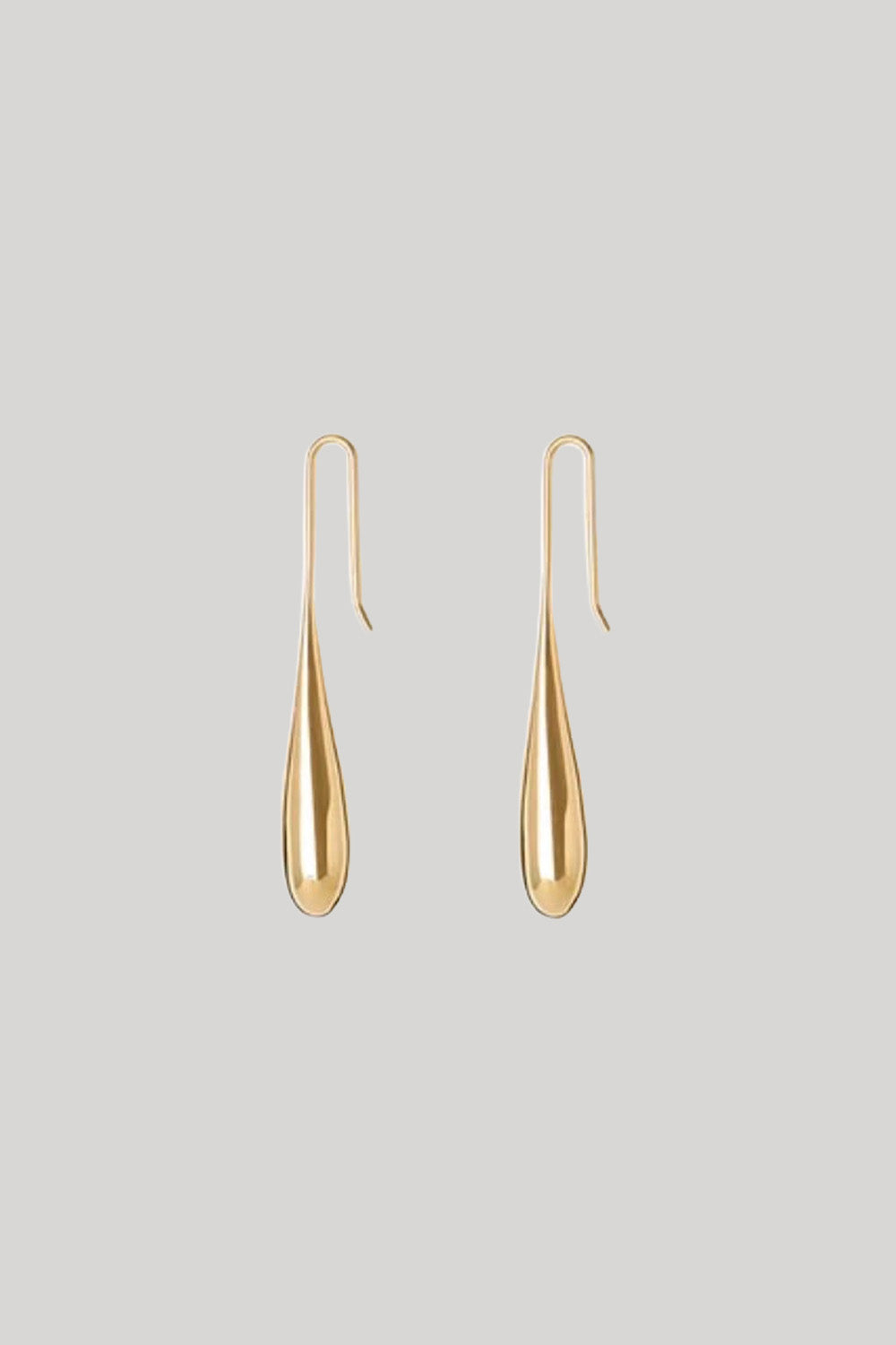 A pair of gold teardrop-shaped dangle earrings with simple hook backs, displayed against a solid light gray background.