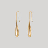 A pair of gold teardrop-shaped dangle earrings with simple hook backs, displayed against a solid light gray background.