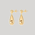 A pair of gold teardrop drop earrings with a polished reflective finish and post-back closures, shown against a solid light gray background.