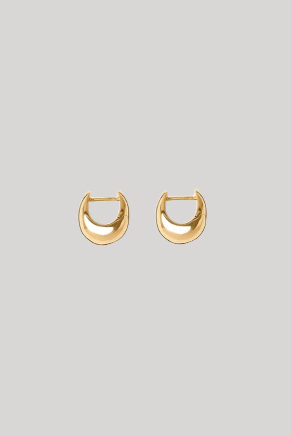 A pair of gold crescent-shaped hoop earrings on a solid light gray background.