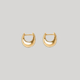 A pair of gold crescent-shaped hoop earrings on a solid light gray background.