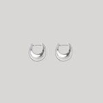A pair of polished silver crescent-shaped hoop earrings on a solid light gray background.
