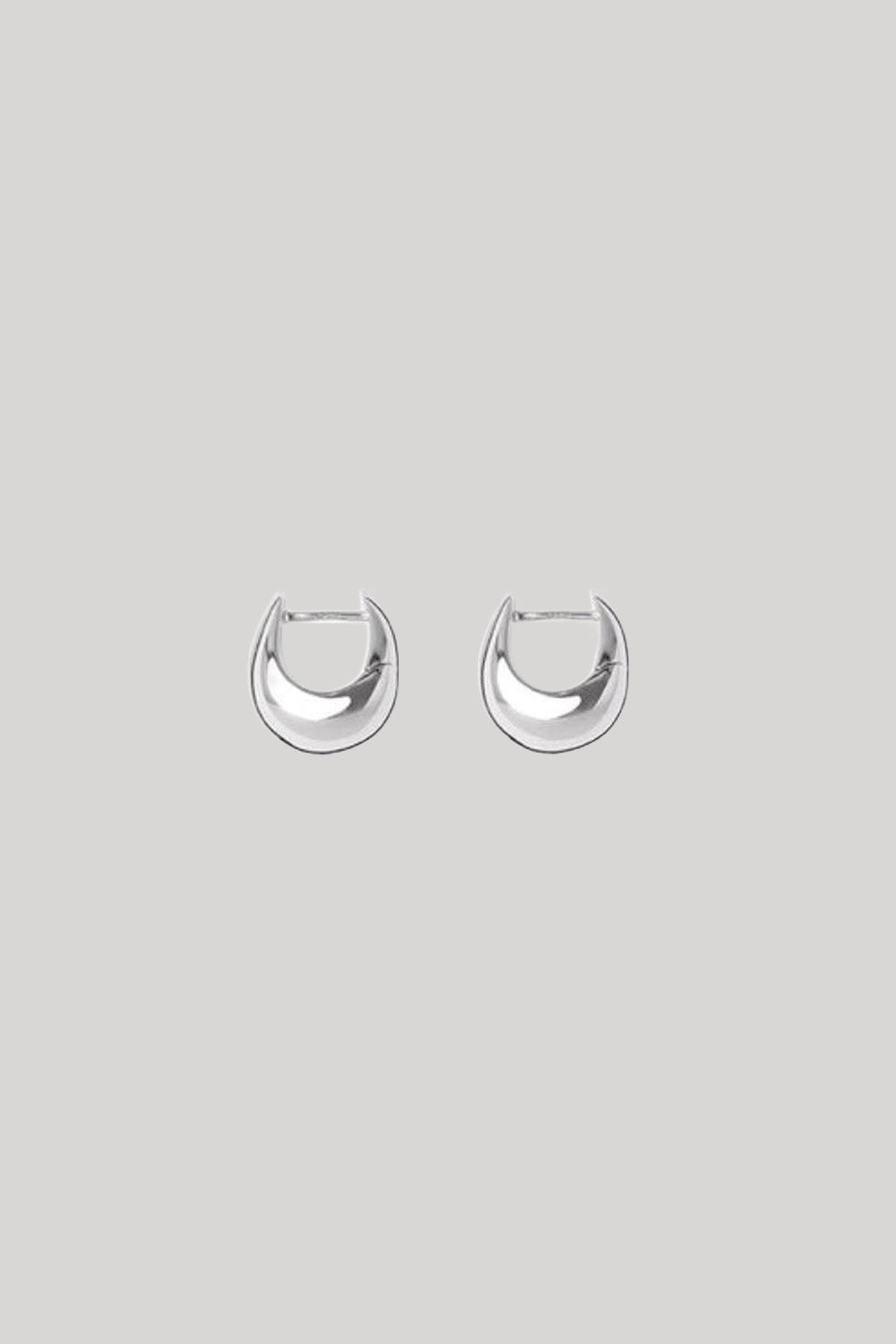 A pair of polished silver crescent-shaped hoop earrings on a solid light gray background.