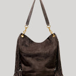 A dark brown suede hobo shoulder bag with long fringe detailing on the sides and a matching shoulder strap, accented by gold-tone hardware, from Nili Lotan, shown against a solid light gray background.