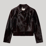 A dark brown cropped pony hair leathre jacket with a pointed collar and three-quarter sleeves, shown flat on a light gray background. The jacket is from Nour Hammour