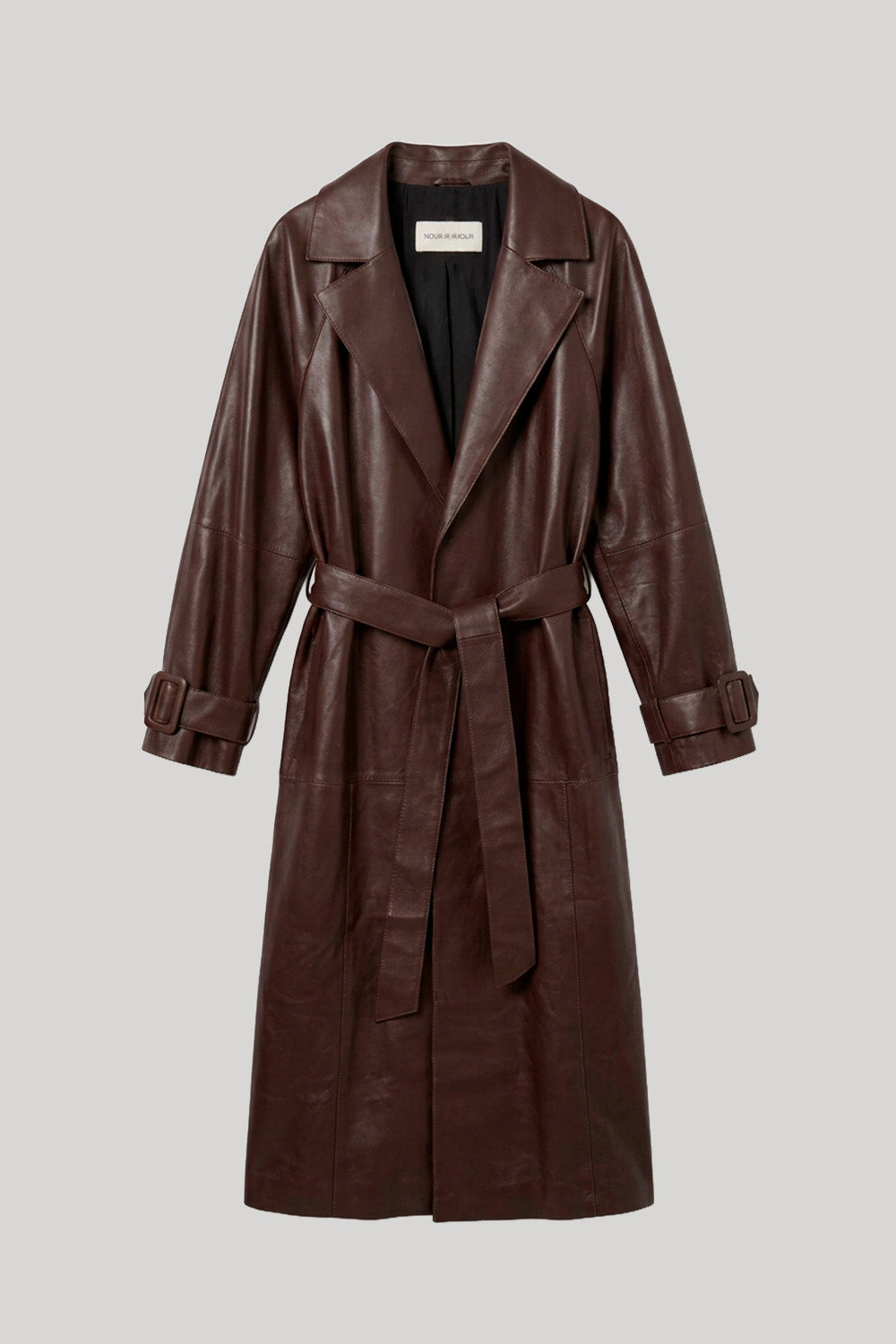 A dark brown leather trench coat with a matching waist tie belt, shown on a neutral light gray background. The jacket is from Nour Hammour