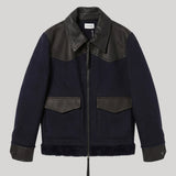 A dark navy blue shearling-style jacket from Parosh with black leather shoulder panels, collar, and cuffs, featuring a front zipper and two flap pockets, shown against a solid gray background.