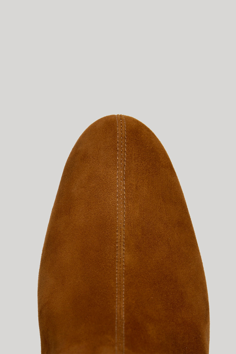 Close-up of the pointed toe of a brown suede boot from Proenza Schouler against a solid light gray background.