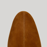 Close-up of the pointed toe of a brown suede boot from Proenza Schouler against a solid light gray background.