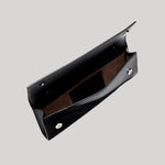 A black leather clutch bag with a brown suede-like interior lining, shown open against a solid light gray background.