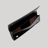 A black leather clutch bag with a brown suede-like interior lining, shown open against a solid light gray background.