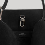 Close-up of the interior of a black tote bag with a silver metal D-ring clasp and a small white 'TOTEME MADE IN ITALY' label stitched inside.