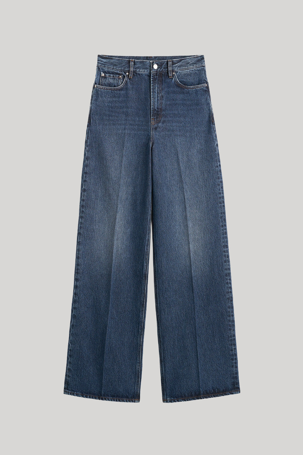 A pair of high-waisted, wide-leg blue denim jeans from Toteme with a faded wash, shown flat against a solid light gray background. 