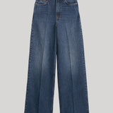 A pair of high-waisted, wide-leg blue denim jeans from Toteme with a faded wash, shown flat against a solid light gray background. 